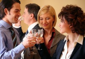 Picture of three people holding champaign glasses at an office party, illustrating that there are 4 things you can do to protect your teeth from alcohol.