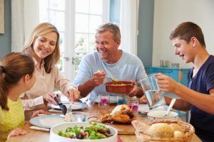 Family sitting at the dinner table, illustrating 7 healthy foods for your teeth