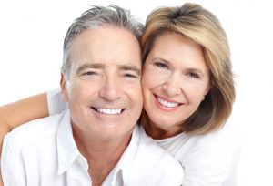 Middle aged caucasian couple smiling into the camera, illustrating the concept that there are 8 things you can do for your teeth to help postpone alzheimer's