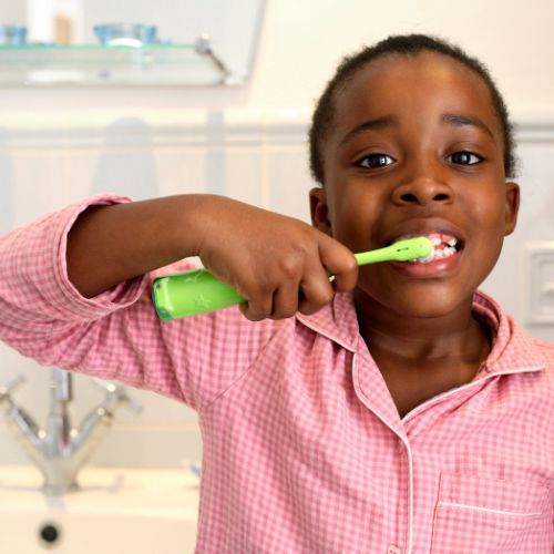 Young black boy in pajamas brushing teeth, illustrating the concept that there is a right way and a wrong way to brush your teeth.